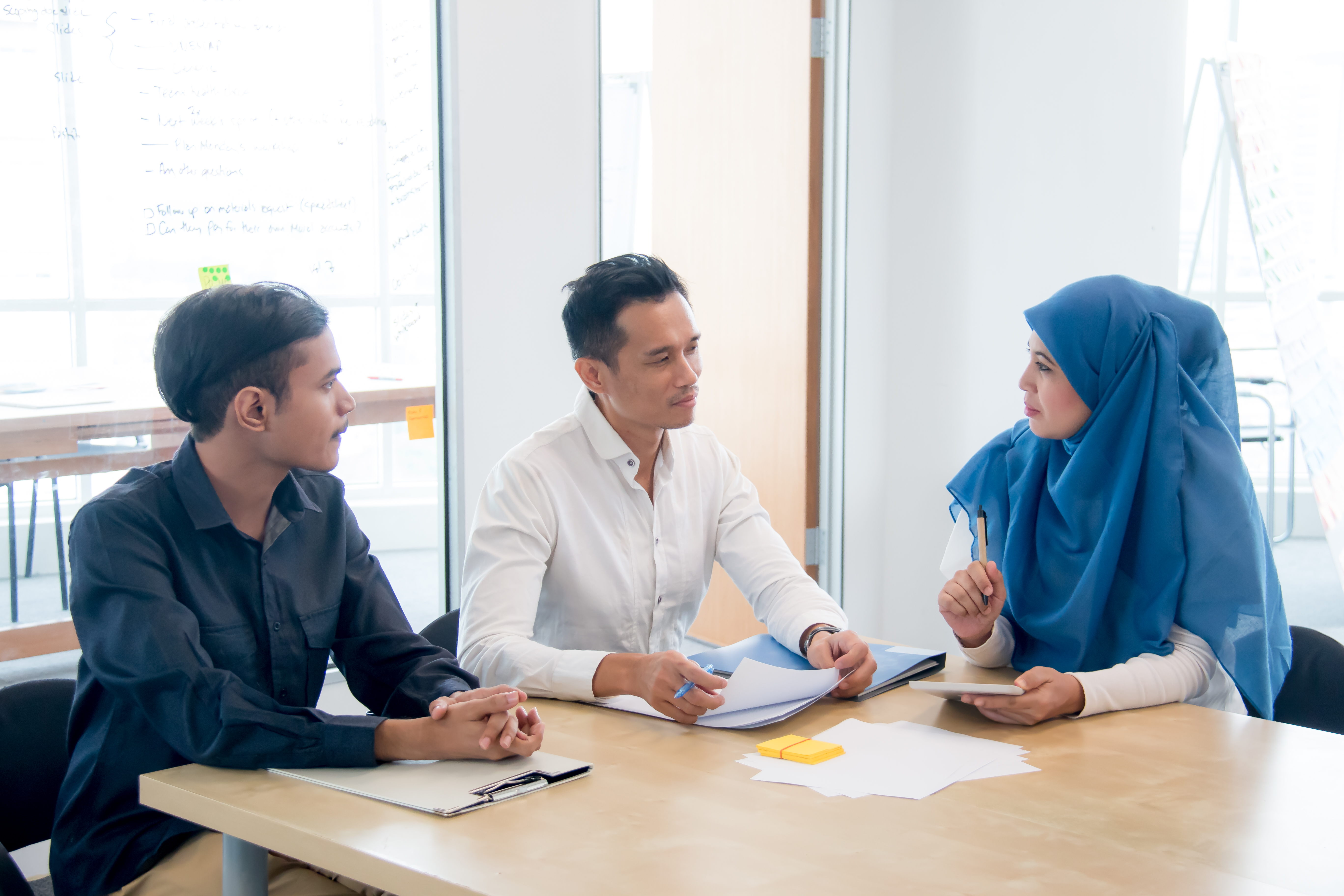 Three people meeting around a table