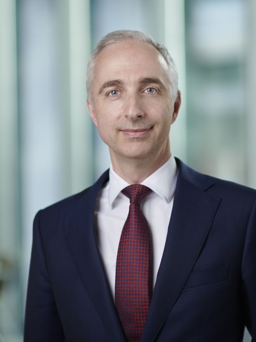 Matthew Hibibins in a suit smiling at the camera